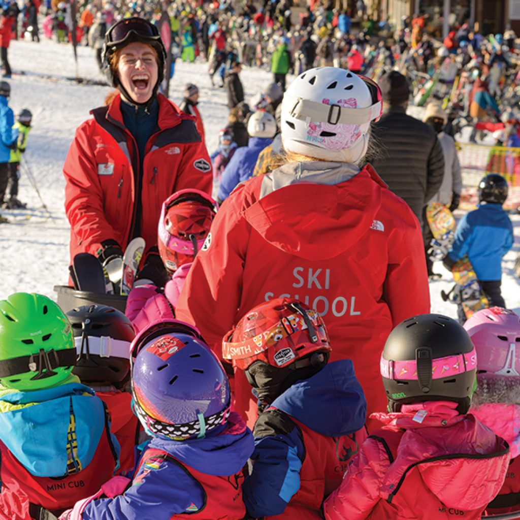 ski instructor laughing and leading a group of kids